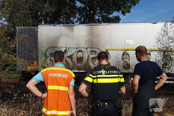 Brand nabij oude trailer in weiland