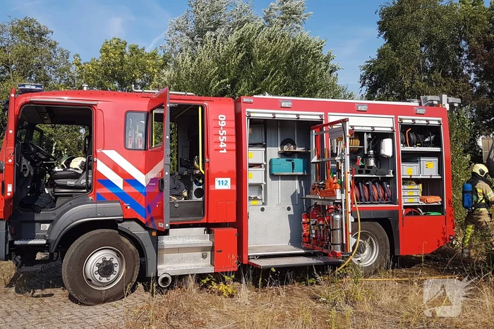 Brand nabij oude trailer in weiland