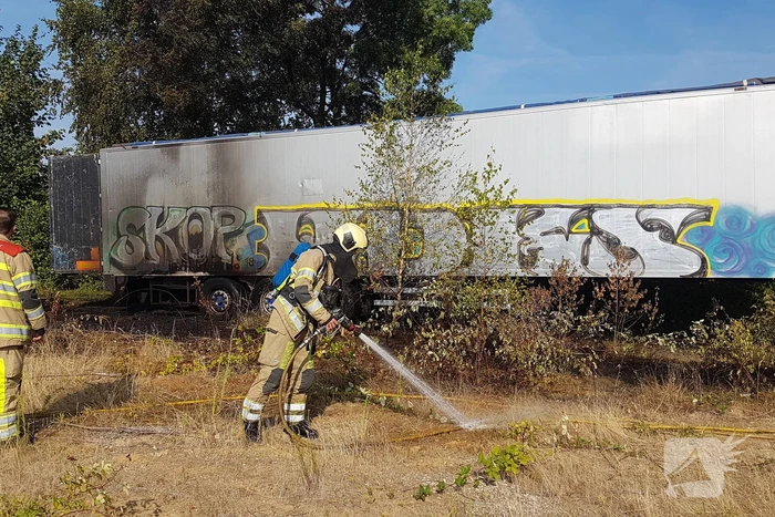 Brand nabij oude trailer in weiland