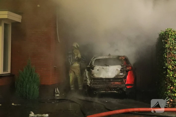 Auto in lichterlaaie onder carport van woning