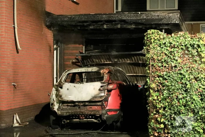 Auto in lichterlaaie onder carport van woning