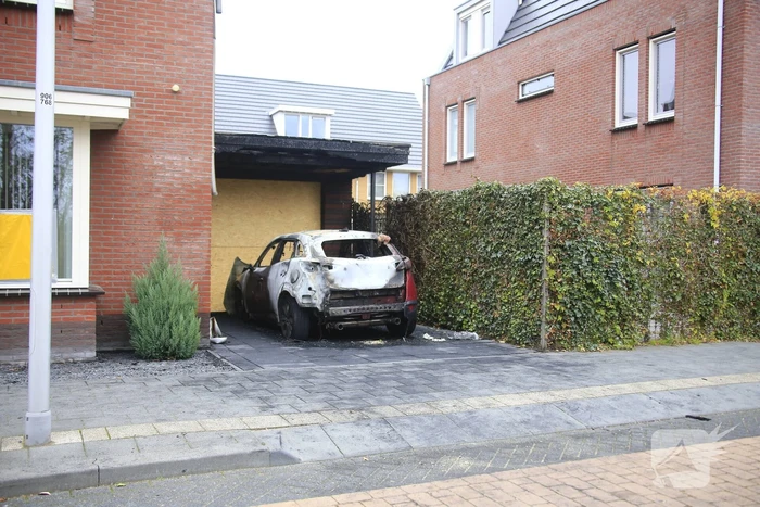 Auto in lichterlaaie onder carport van woning
