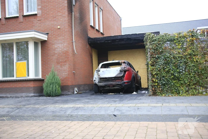 Auto in lichterlaaie onder carport van woning