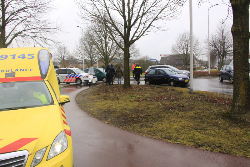 Auto en scooter botsen op rotonde