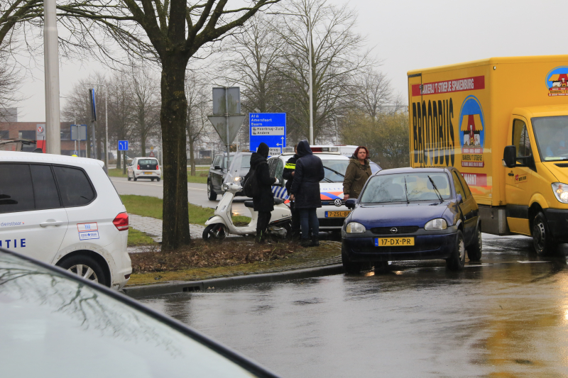 Auto en scooter botsen op rotonde