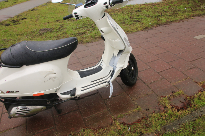 Auto en scooter botsen op rotonde