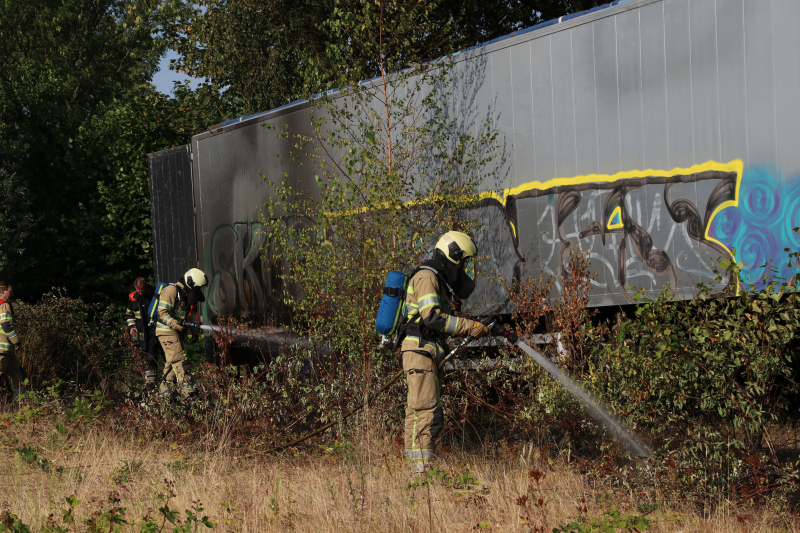 Brand nabij oude trailer in weiland