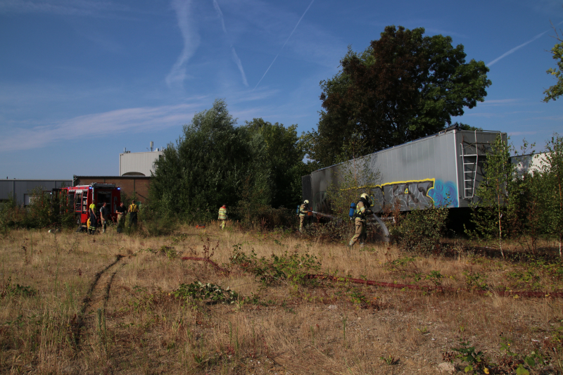 Brand nabij oude trailer in weiland