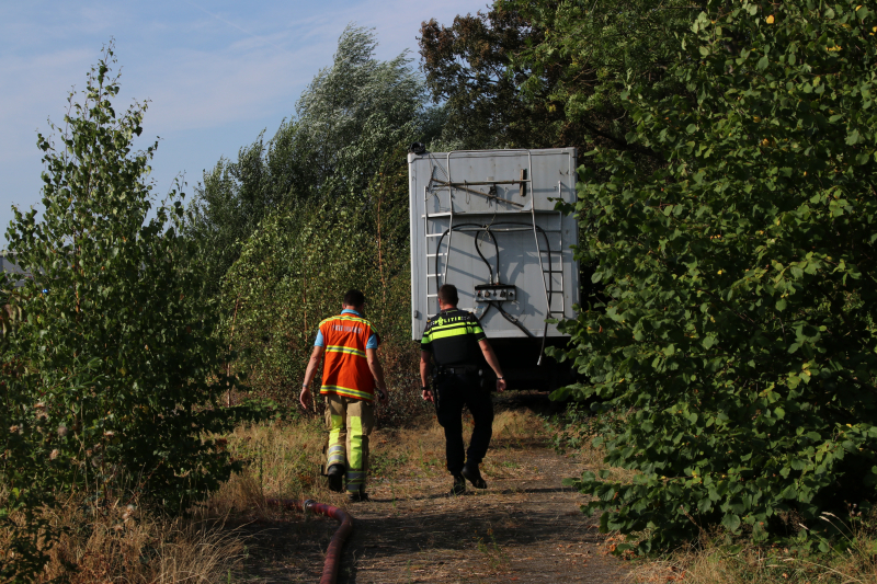 Brand nabij oude trailer in weiland