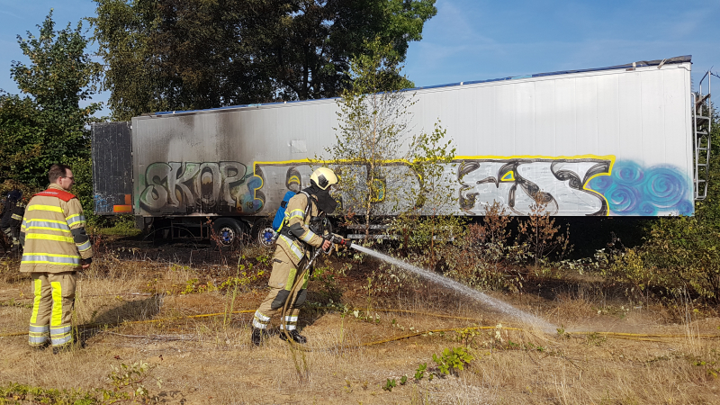 Brand nabij oude trailer in weiland