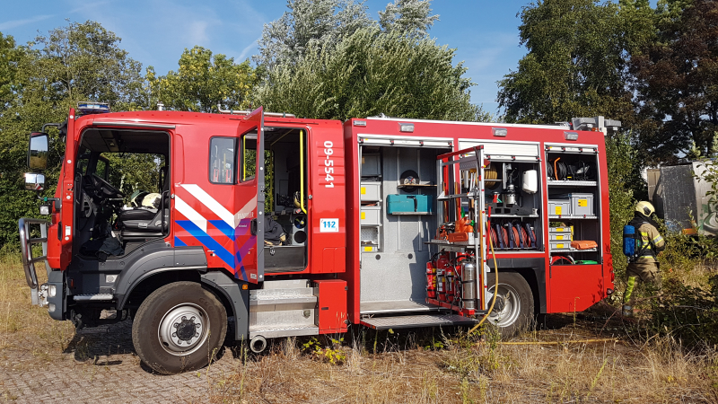 Brand nabij oude trailer in weiland