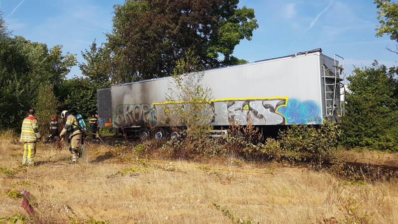 Brand nabij oude trailer in weiland