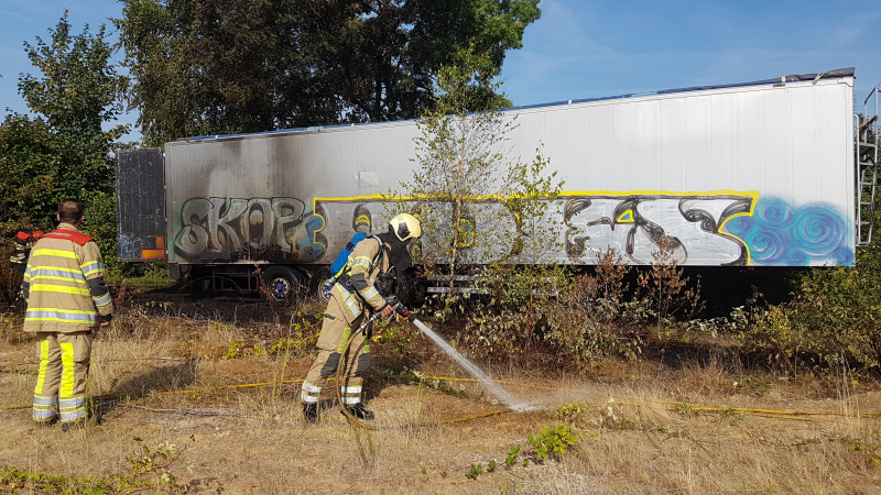 Brand nabij oude trailer in weiland
