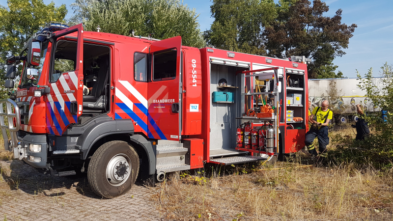Brand nabij oude trailer in weiland