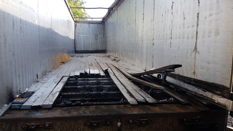 Brand nabij oude trailer in weiland