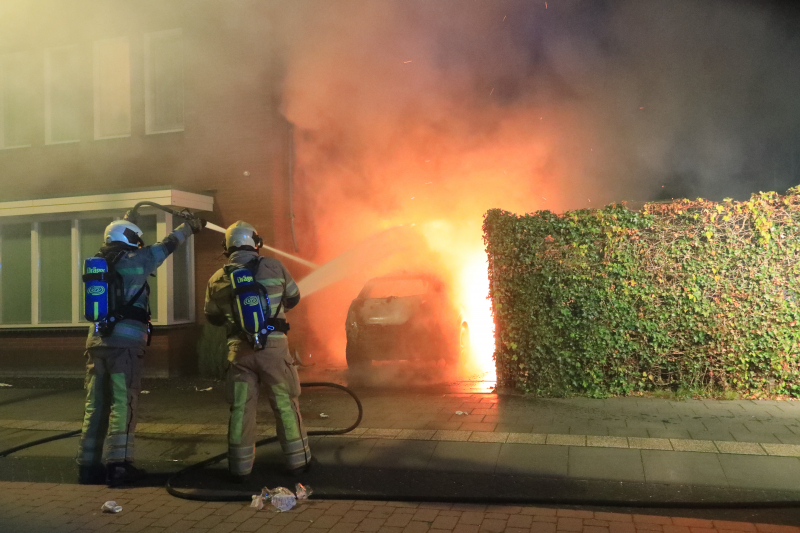 Auto in lichterlaaie onder carport van woning