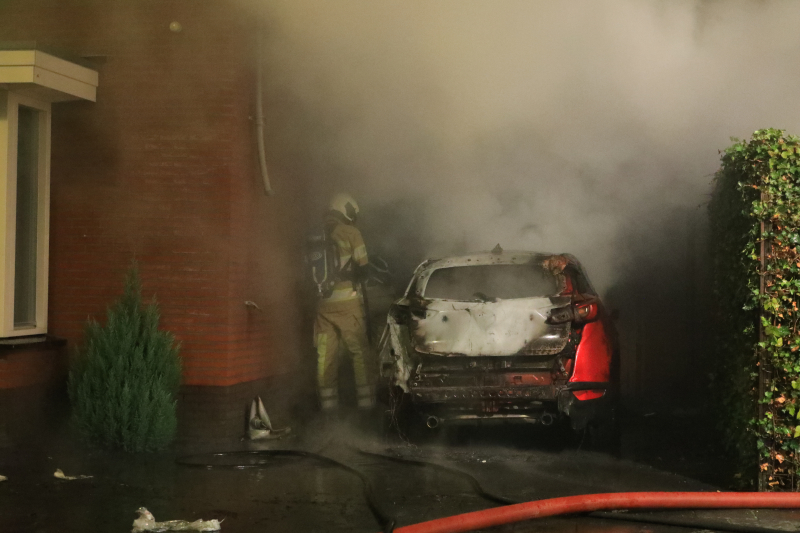 Auto in lichterlaaie onder carport van woning