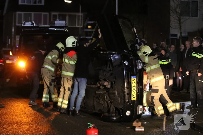 Bestuurster bekneld na auto op zijn kant
