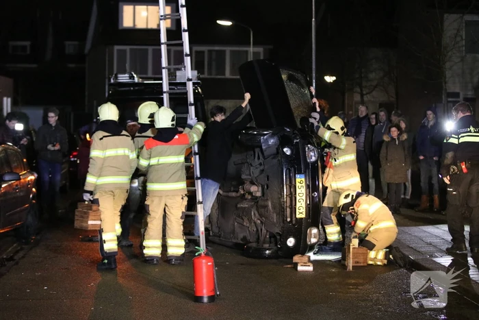 Bestuurster bekneld na auto op zijn kant