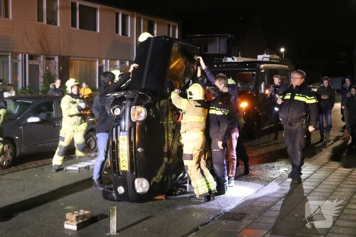 Bestuurster bekneld na auto op zijn kant