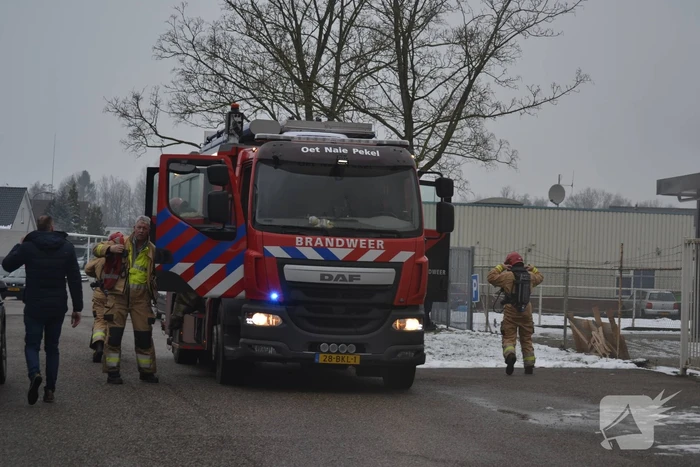 Houtopslag tegen loods aan vat vlam