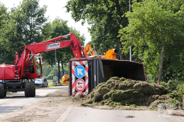 Kar met maai-afval achter trekker kantelt