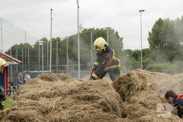 Brandweer blust smeulende hooibalen