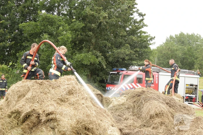 Brandweer blust smeulende hooibalen