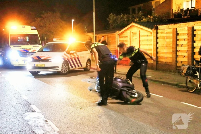 Snorscooter klapt op paal bij oversteekplaats, jonge dame buiten westen