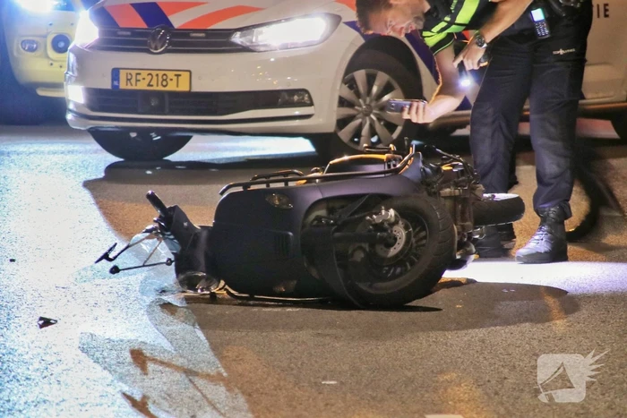 Snorscooter klapt op paal bij oversteekplaats, jonge dame buiten westen