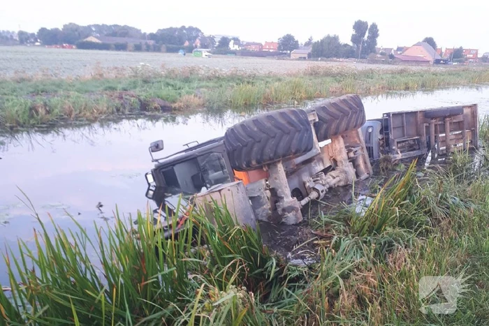 Graafmachine met aanhanger belandt te water