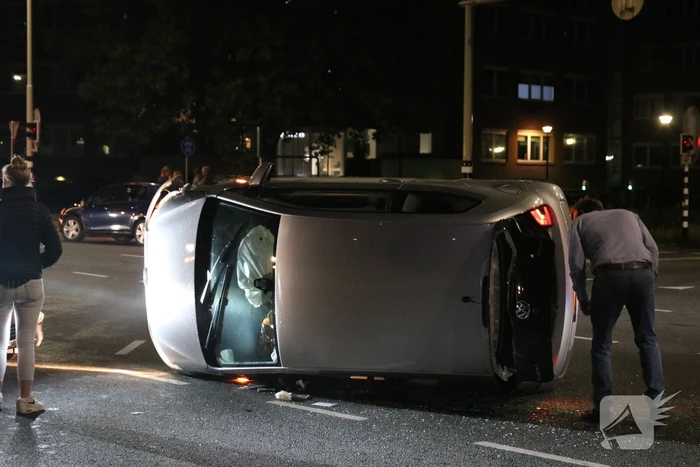 Auto belandt op zijkant na botsing; inzittende gewond bij reddingsactie