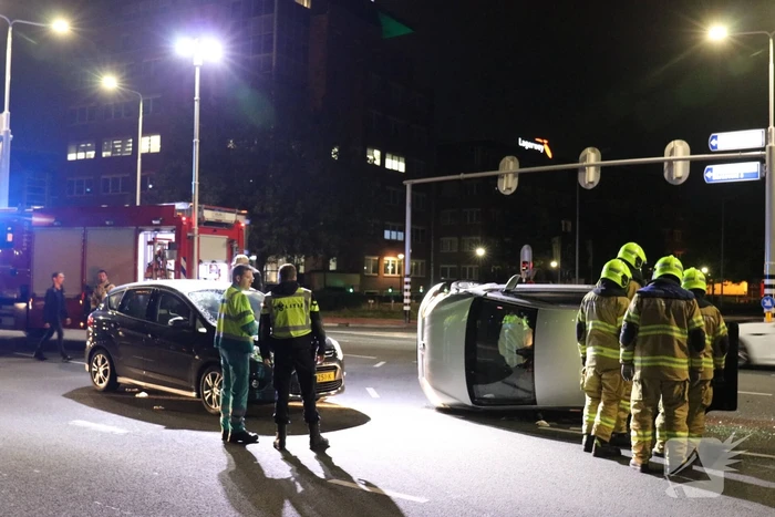 Auto belandt op zijkant na botsing; inzittende gewond bij reddingsactie