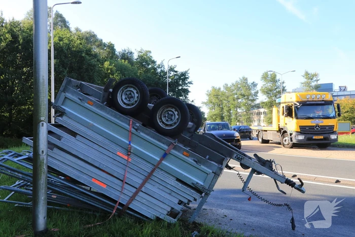 Aanhangwagen met steigerdelen kantelt