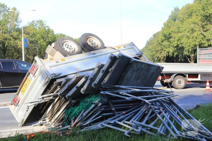 Aanhangwagen met steigerdelen kantelt