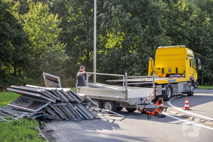 Aanhangwagen met steigerdelen kantelt