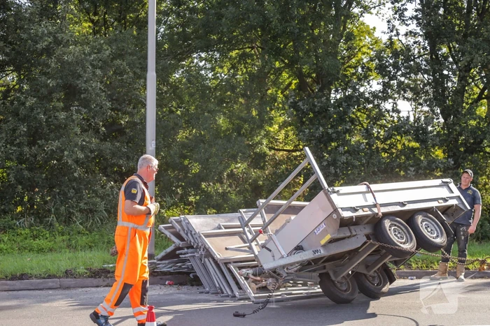 Aanhangwagen met steigerdelen kantelt
