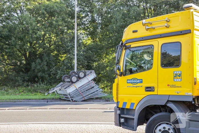 Aanhangwagen met steigerdelen kantelt