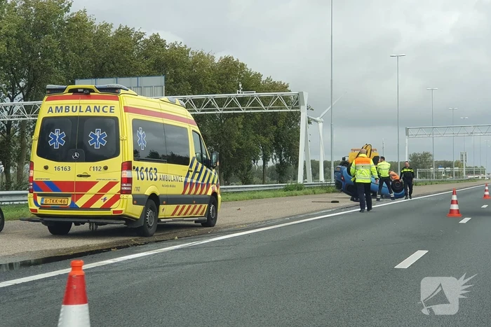 Auto over de kop naast snelweg