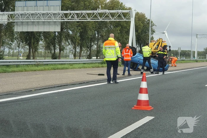 Auto over de kop naast snelweg