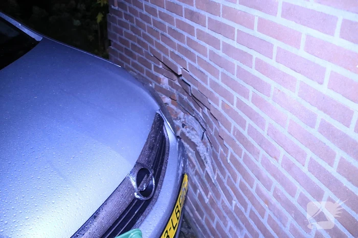 Geparkeerde auto ramt gevel na aanrijding