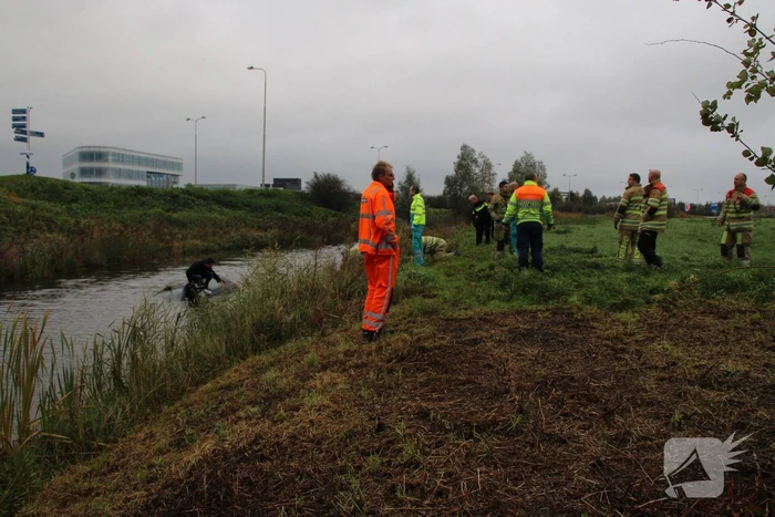 Bestuurder klimt op dak van te water geraakte auto
