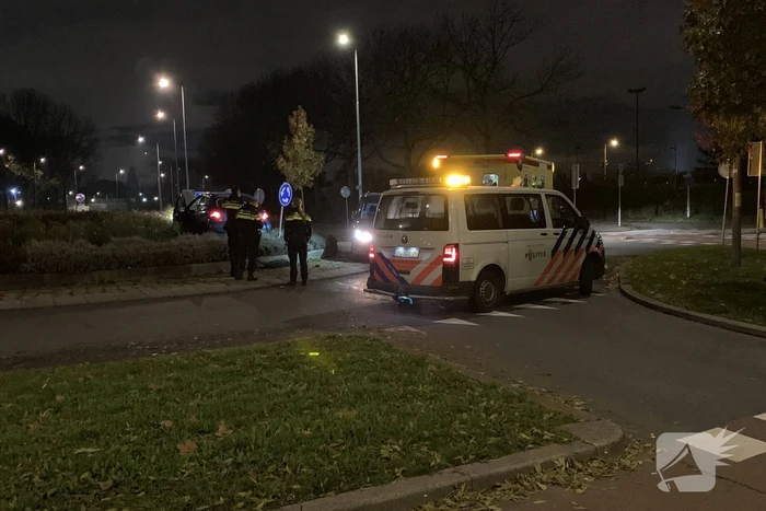 Auto belandt bovenop bosjes op rotonde