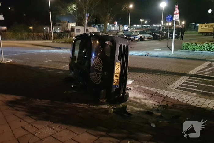 Auto op zijn kant na botsing met lantaarnpaal