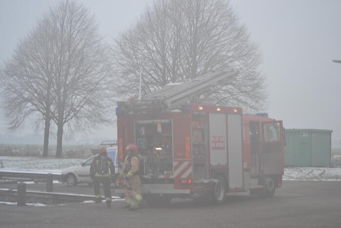 Houtopslag tegen loods aan vat vlam