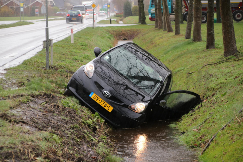 Auto schiet over kruising de sloot in