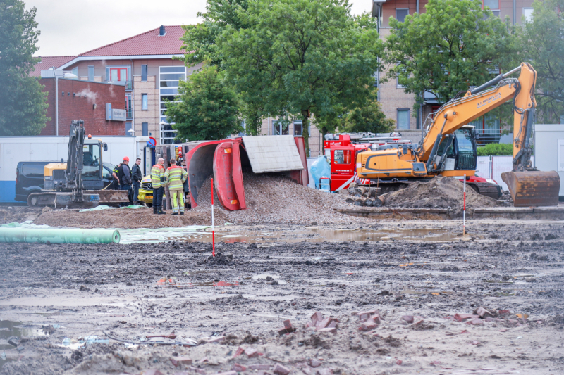 Vrachtwagen kantelt op bouwterrein
