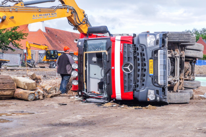 Vrachtwagen kantelt op bouwterrein