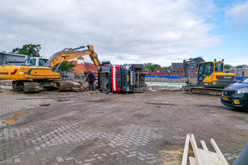 Vrachtwagen kantelt op bouwterrein