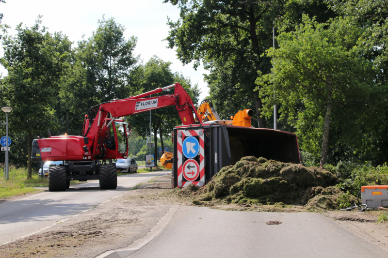Kar met maai-afval achter trekker kantelt